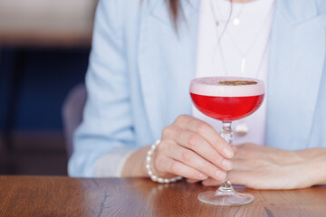 girl holding a glass with a cocktail in a cafe or restaurant: close-up, restaurant concept