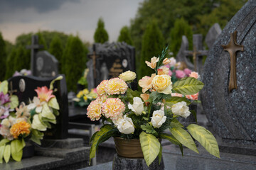 Beautiful artificial bouquet on the grave with crosses in the background.