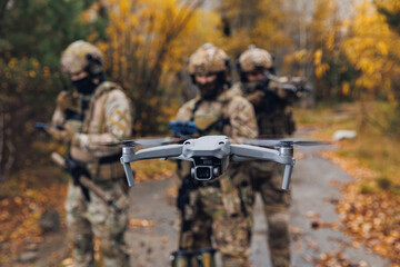 Modern army soldiers using aerial drone for artillery guidance and scouting view enemy positions in...