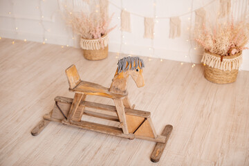Fototapeta na wymiar Antique wooden toy horse on the floor of spacious bedroom. Happy childhood memories concept.
