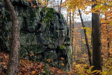 A large, mossy rock protrudes from a forest in the fall overlooking rolling hills. Algonquin Provincial Park, Ontario, Canada.
