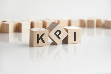 text KPI on wooden blocks with letters on a white background. reflection of the caption on the mirrored surface of the table