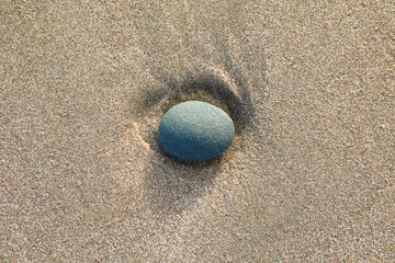 Fototapeta na wymiar Lone gray rock in the yellow sand