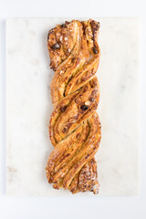 One delicious braid pastry covered with raisins, laminated almonds and icing sugar on a marble...