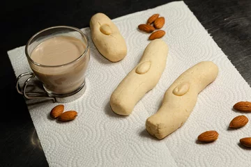Foto op Plexiglas Closeup shot of long almond cookies on a napkin along with almonds and a cup of coffee © Luis Alfredo Gonzalez Calkech/Wirestock Creators