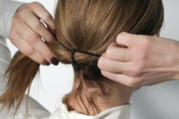Serie of photos of making a low ponytail with basic elastic hair band. Back view of young woman...