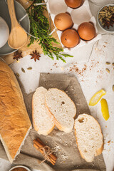 Ingredients for preparing spanish torrijas, french toasts  or traditional Portuguese rabanadas for Christmas. Typical sweet food for Christmas with slices of bread, eggs, cinnamon, milk and lemon peel