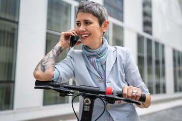 woman mature senior use mobile phone stand by electric kick scooter