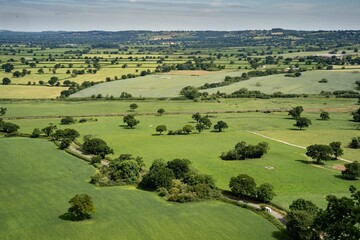 Arial shot of the green fields surrounded by trees and bushes
