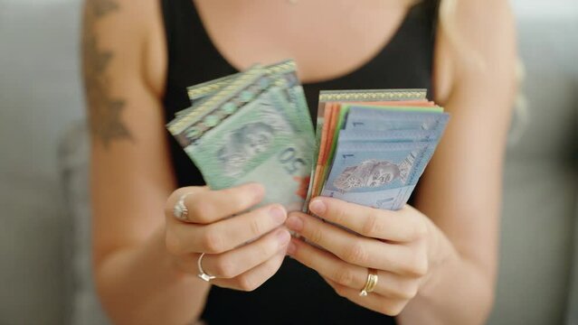 Young woman counting malaysia ringgit banknotes at home