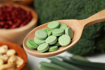 Wooden spoon of pills over foodstuff, closeup. Prebiotic supplements