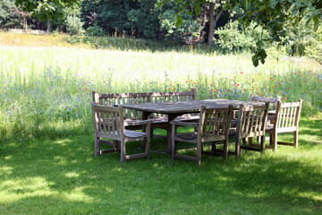 Empty wooden table with bench and chairs in garden