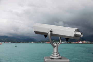 Metal tower viewer installed near sea, space for text. Mounted binoculars