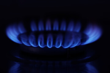 Gas burner with burning flame in darkness, closeup