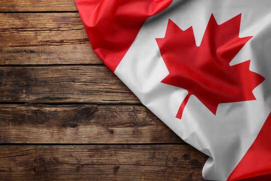 Flag of Canada on wooden table, top view. Space for text