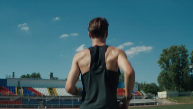 A professional athlete runs through an empty stadium on a bright summer day. Handheld camera