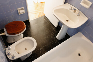 Fototapeta premium Full classic bathroom with white slab artifacts black floor tiles and lavander blue wall tiles on a high view