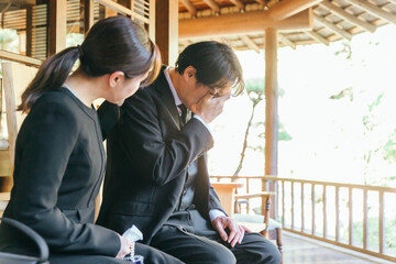 お葬式で泣く喪服を着た遺族の日本人男女
