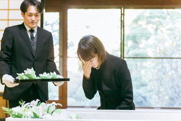 お葬式の納棺で花入れの儀をする日本人女性（号泣）
