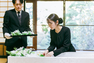 お葬式の納棺で花入れの儀をする日本人女性
