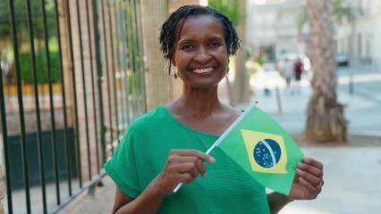 Middle age african american woman smiling confident holding brazil flag at street - Powered by Adobe