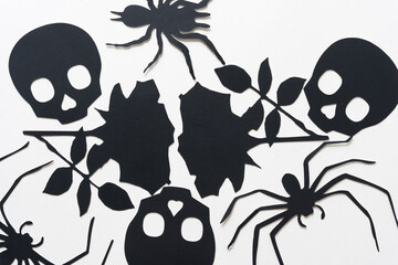 black paper silhouettes of spiders, roses, and skull heads on blank paper