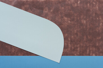 two paper shapes (one gray with rounded corner) and one blue (border) on dark brown tissue paper