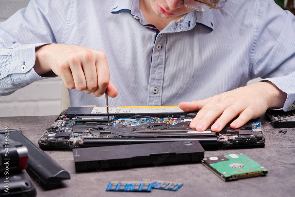 Aufkleber notebook repair. man disassembles a laptop. removes the keyboard. computer service and repair concep