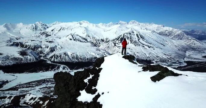 Aerial Forward Shot Of Man With Ski Poles Looking At View Of Glacier From Mountain Top - Canwell Glacier, Alaska