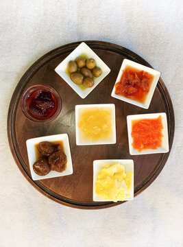 Seven Dishes of Condiments on a Wood Tray from Above