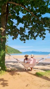 A couple of men and women in a hammock on a tropical beach in Koh Mka Thailand