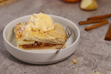 piece of an apple strudel roll with cinnamon and ice cream on top
