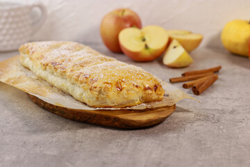 apple pastry strudel roll with cinnamon on grey marble table
