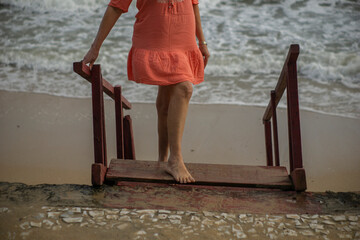 elderly woman enjoying trip, blue sky in the background, on a beach on the stairs
