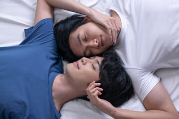 Obraz na płótnie Canvas High angle view of smiling Asian gay couple relaxing and lying down in bed. LGBT male couple lifestyle concept.