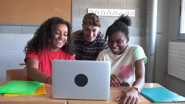 Multiracial group of high school students doing homework research together using laptop in class. 4k handheld video.