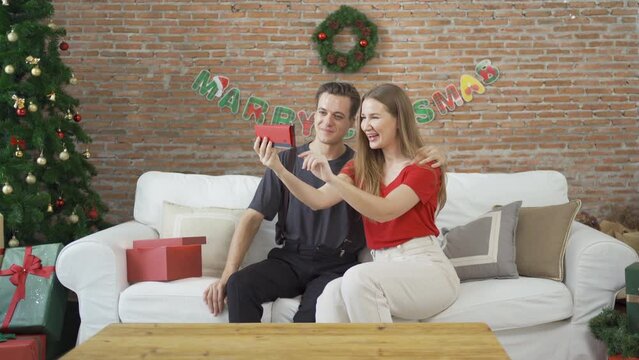 Portrait of a couple of caucasian taking a selfie together by phone. They have a celebration in party on Merry Christmas Eve Xmas on holiday at home or house. People lifestyle. Romance