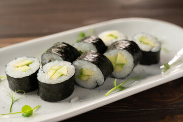 Sushi with avocado, rice in seaweed on wooden table. Japanese, Asian healthy food.