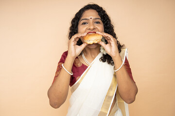 South indian woman wear sari enjoy burger fast food or junk food snack unhealthy eating lifestyle, ...