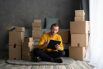 business men sit on floor checking customer order online shipping boxes at home. Starting Small...