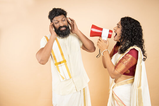 South Indian Woman Scream Or Shouting At Man In Megaphone To Tease Him Isolated On Beige Background. Announce Discounts Sale.