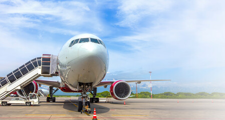 Airplane with a passenger boarding steps on the airport apron - obrazy, fototapety, plakaty