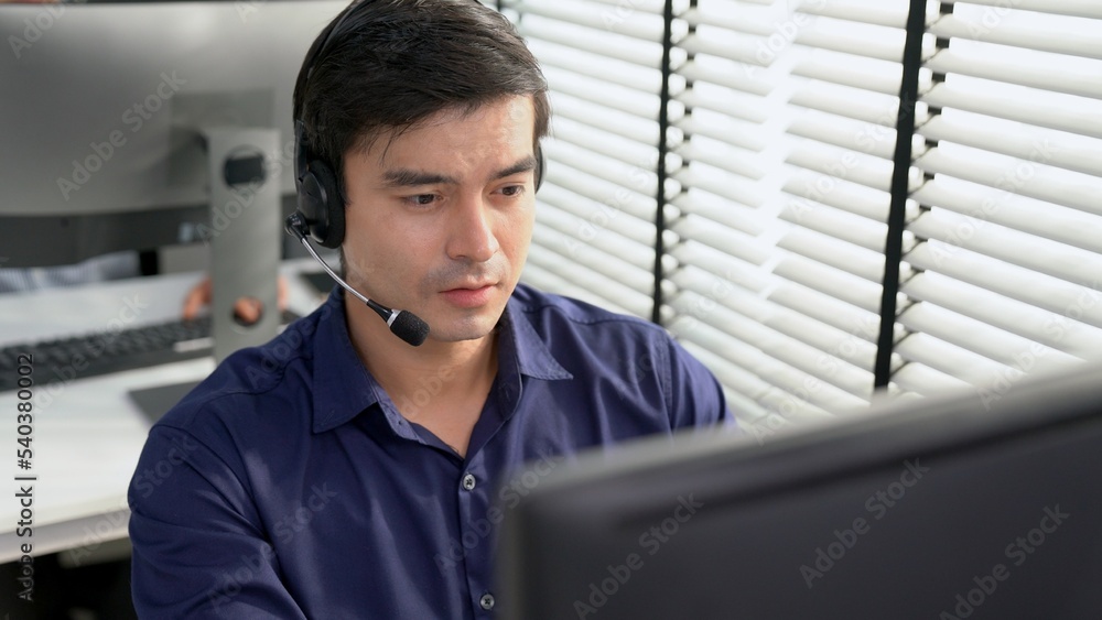 Aufkleber young competent asian male call center agent working at his computer while simultaneously speaking w