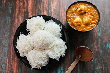 Noolappam Idiyappam rice noodles a popular traditional steam cooked Kerala breakfast dish with hot and spicy egg roast curry on a houseboat Alleppey India. South Indian food. noolputtu Sri lankan