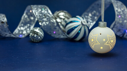 christmas decoration with silver ribbon and glass balls on blurred blue background