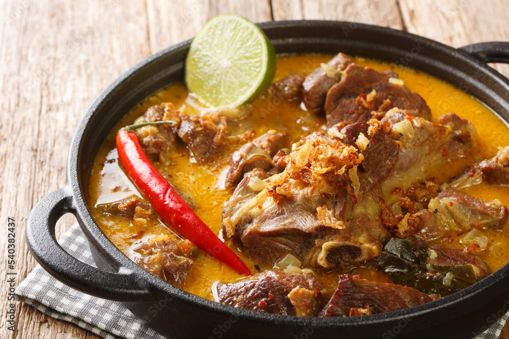 Wall mural Gulai Kambing or Indonesian Traditional Delicious Goat Curry closeup on the pan on the wooden table. Horizontal