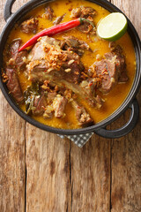 Gulai kambing is Indonesian traditional food, type of food containing rich, spicy and succulent curry closeup on the pan on the wooden table. Vertical top view from above