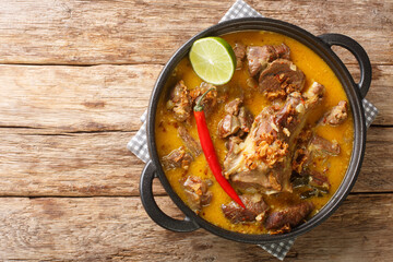 Indonesian food gulai kambing goat curry spicy stew closeup on the pan on the wooden table....