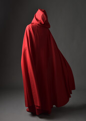 Full length portrait of woman wearing red medieval fantasy costume, flowing hooded cloak. Standing...