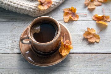 Autumn mood, autumn atmosphere. A cup of coffee, a knitted scarf, books and autumn leaves on the windowsill.